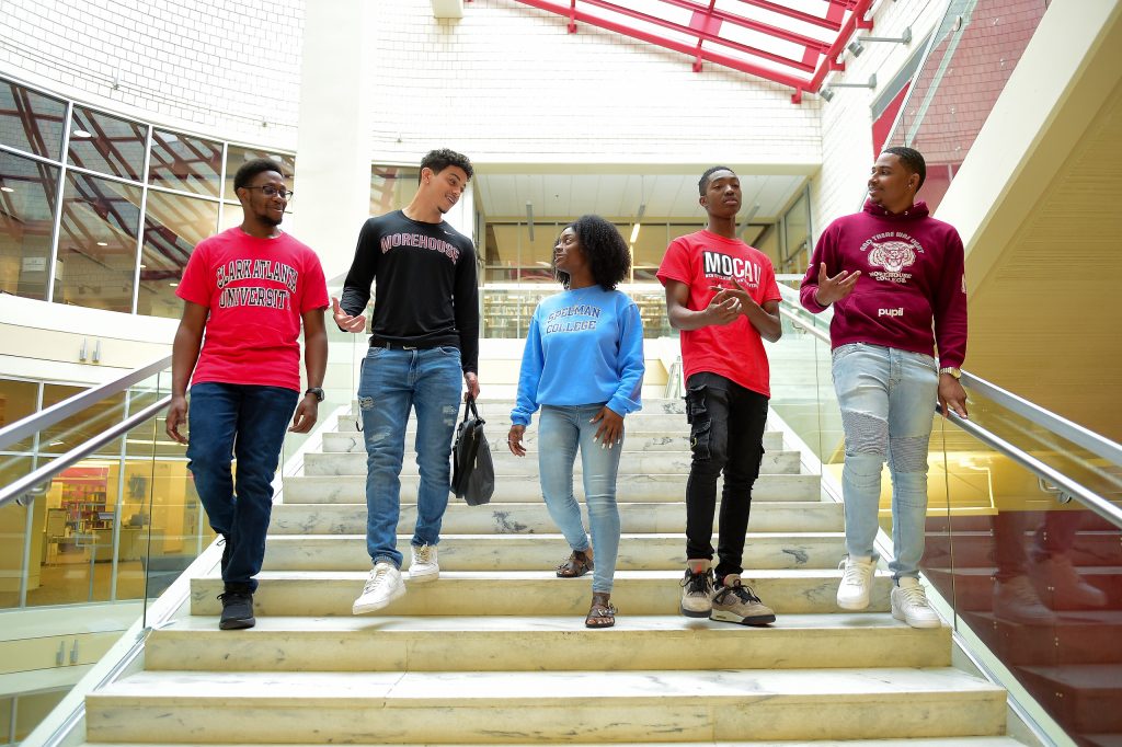 Students walking down steps, each wearing an AUC school sweatshirt.